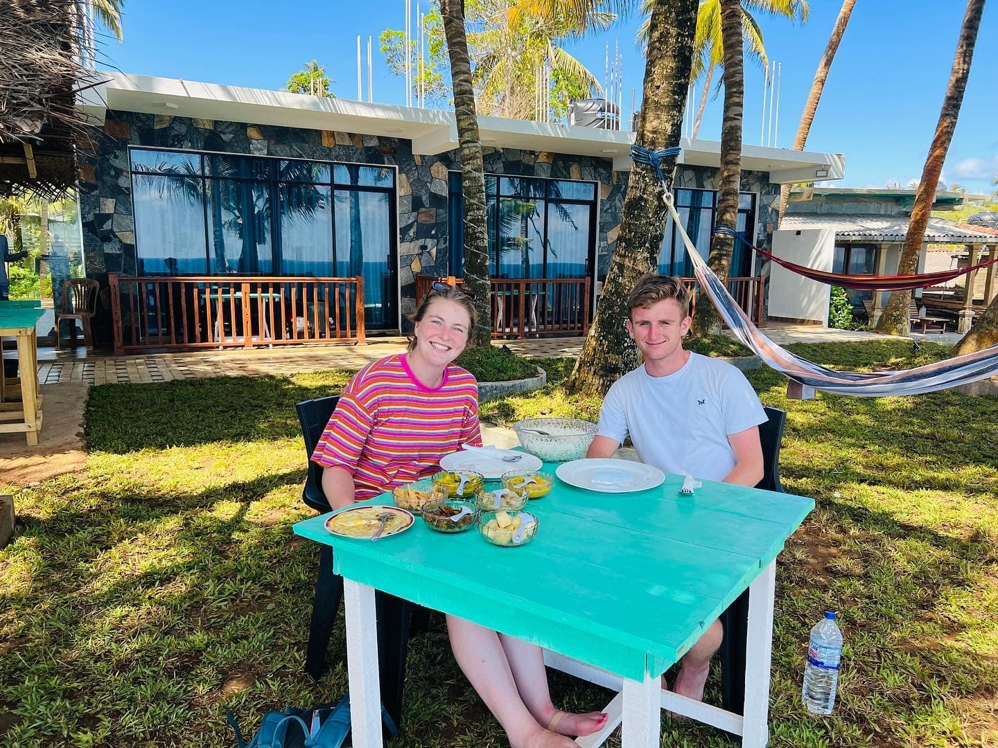 Two guests at breakfast at a turquoise table in front of the rooms
